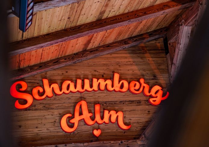 Holzwand mit einem leuchtenden Schriftzug des Schaumberg Alm Logos