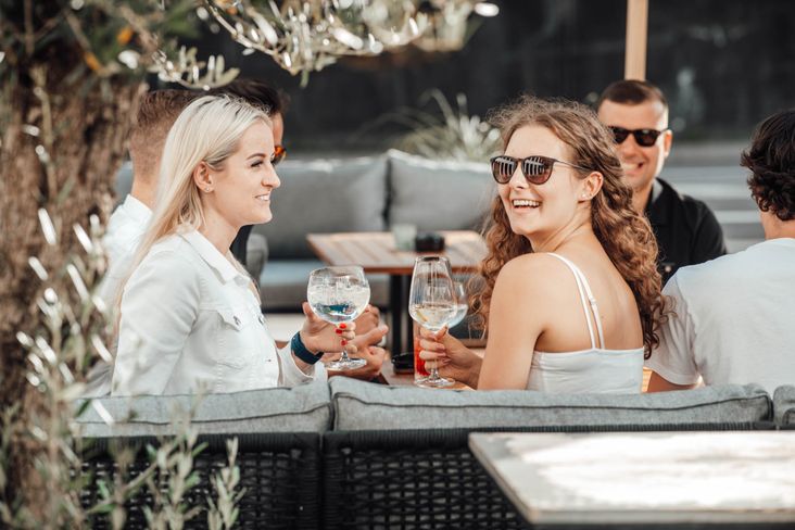 Gruppe von Freunden die auf der Terasse einer Bar Getränke genießt und sich unterhält