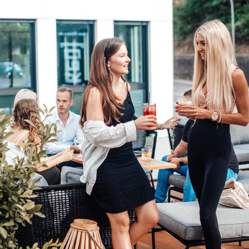 Gruppe von Freunden die auf der Terasse einer Bar Getränke genießt und sich unterhält