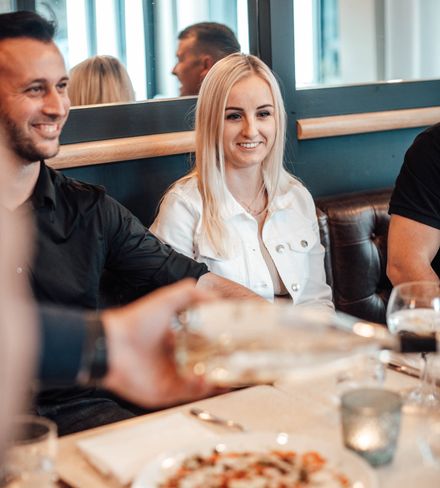 Gruppe von Freunden, die miteinander an einem Restauranttisch sitzt und isst