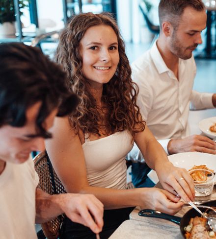 Gruppe von Freunden, die miteinander an einem Restauranttisch sitzt und isst